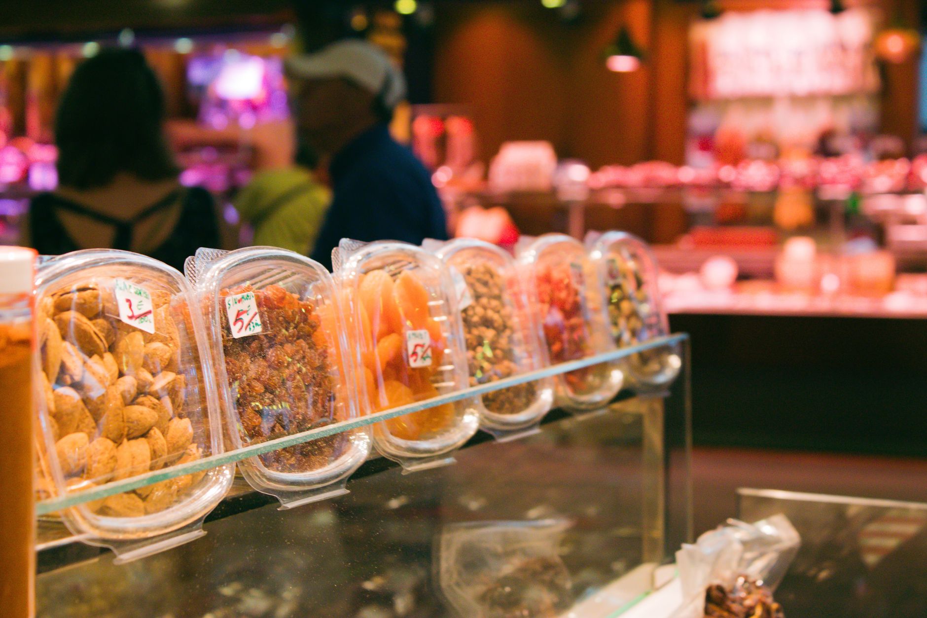 Colorful display of dried fruits and nuts in a bustling Barcelona market.