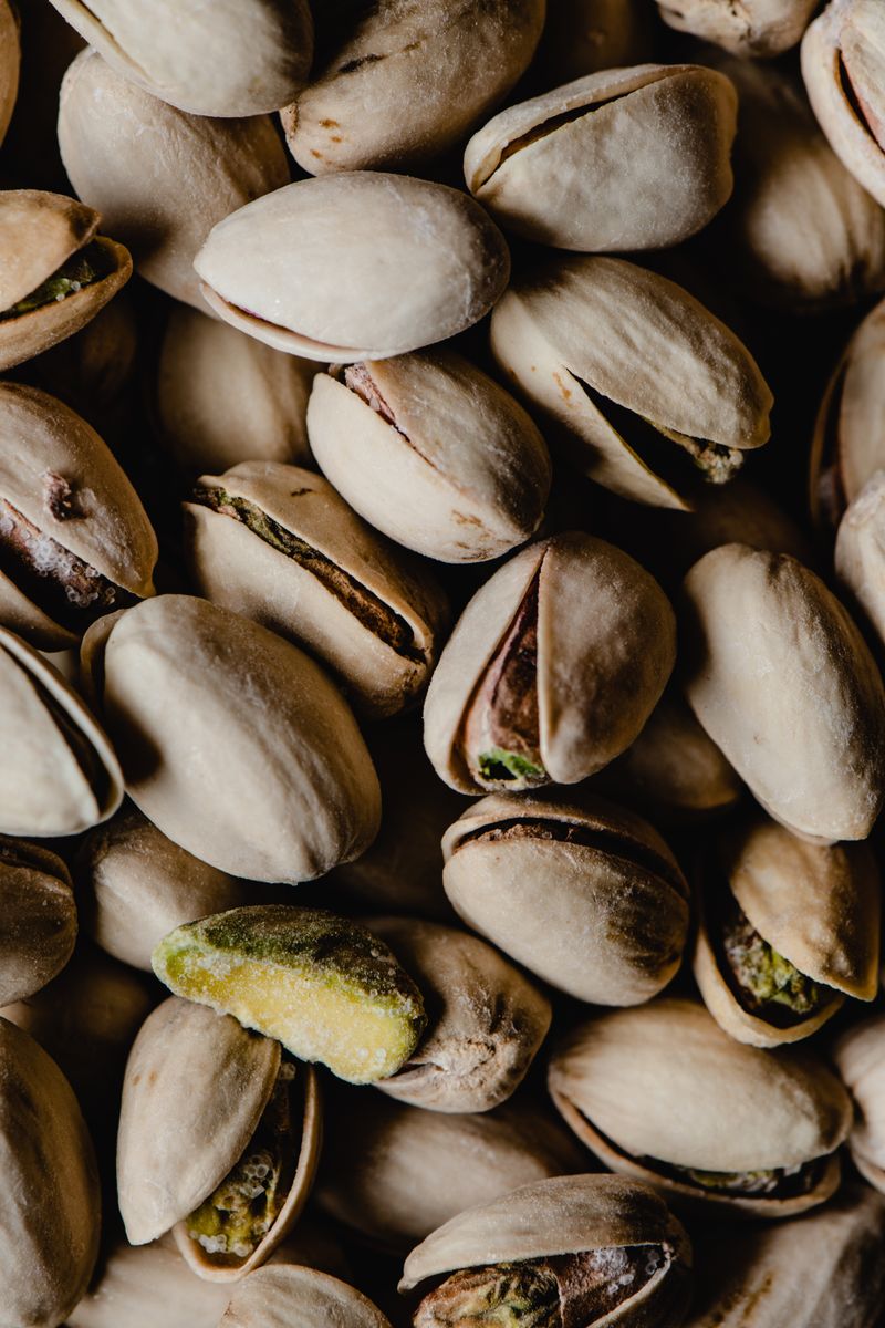 Detailed close-up of unshelled pistachio nuts, ideal for food or culinary themes.